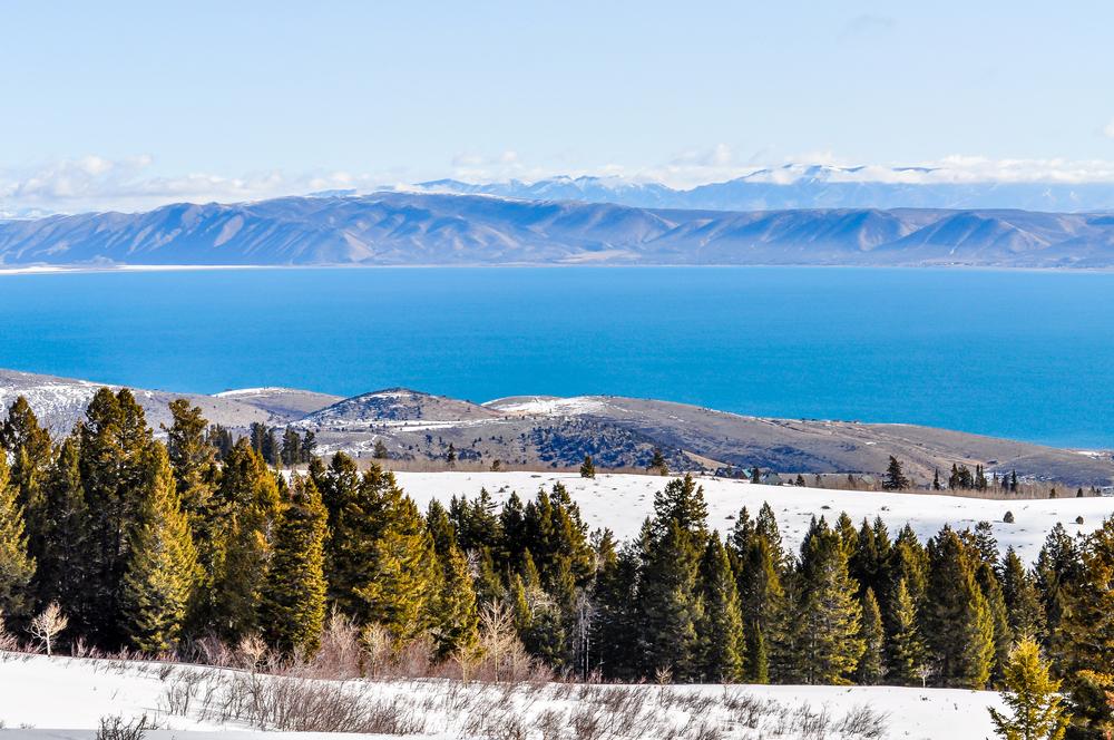 Trees and snow stand high above the blue waters of Bear Lake in Utah.