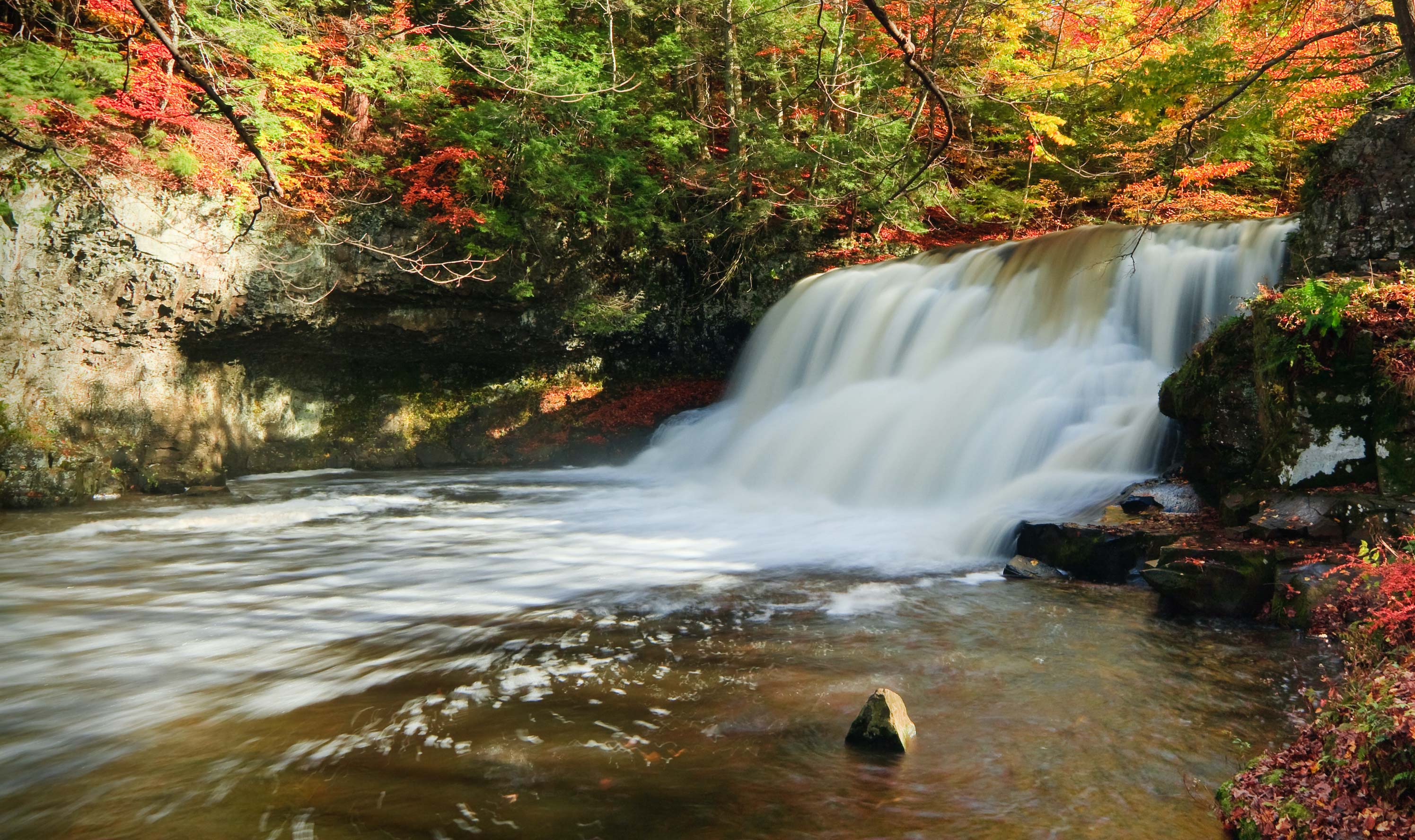 Wadsworth Falls surrounded by trees in Autumn.