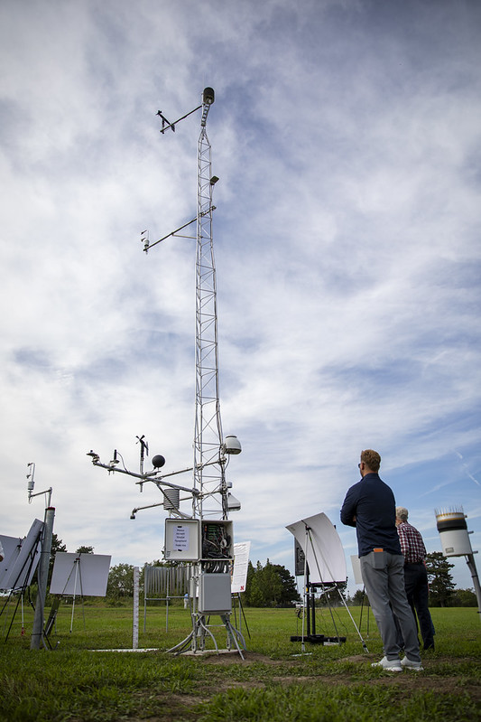 Two mean stand looking up at a new mesonet station.