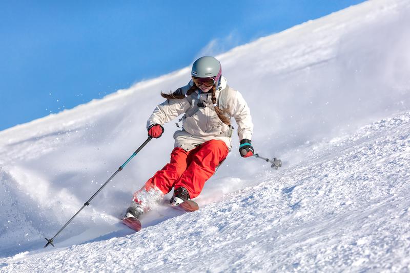 A skier riding downhill on a sunny day
