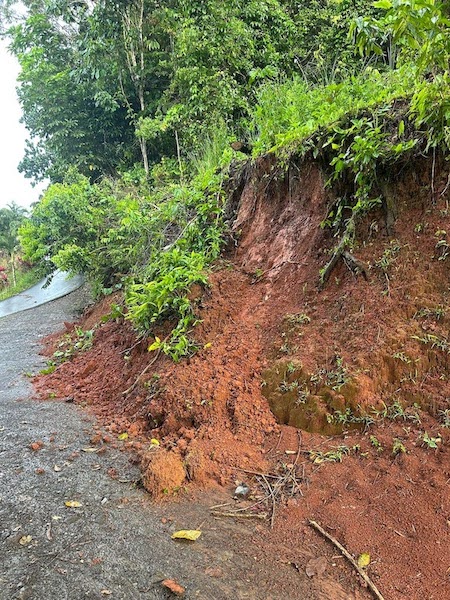 This photo is showing loose red-orange soil that slid from the top onto a gravel road.