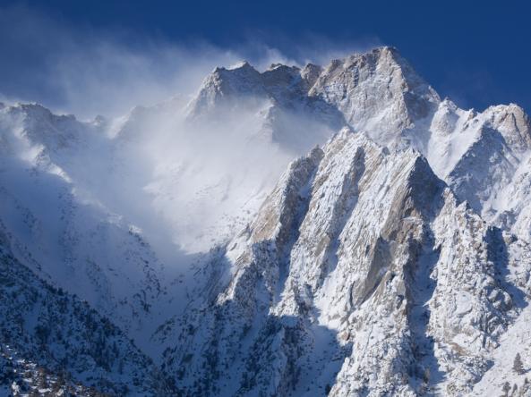 Wind blows snow off of steep, snow-covered peaks in the eastern Sierra Nevada. 