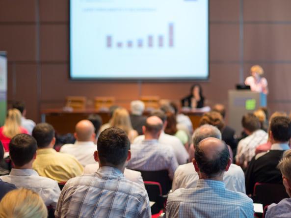 An audience listens to a presentation at a conference