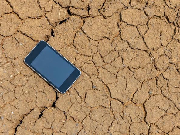 A smartphone laying on dry, cracked ground
