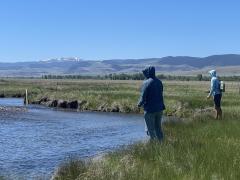 Two anglers on the banks on a Montana river with snow-capped mountains in the background. Photo by the U.S. Geological Survey.