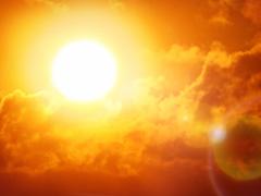 The sun shines brightly among clouds in a red sky, representing a heat wave. Photo credit: Shutterstock, Ed Connor.