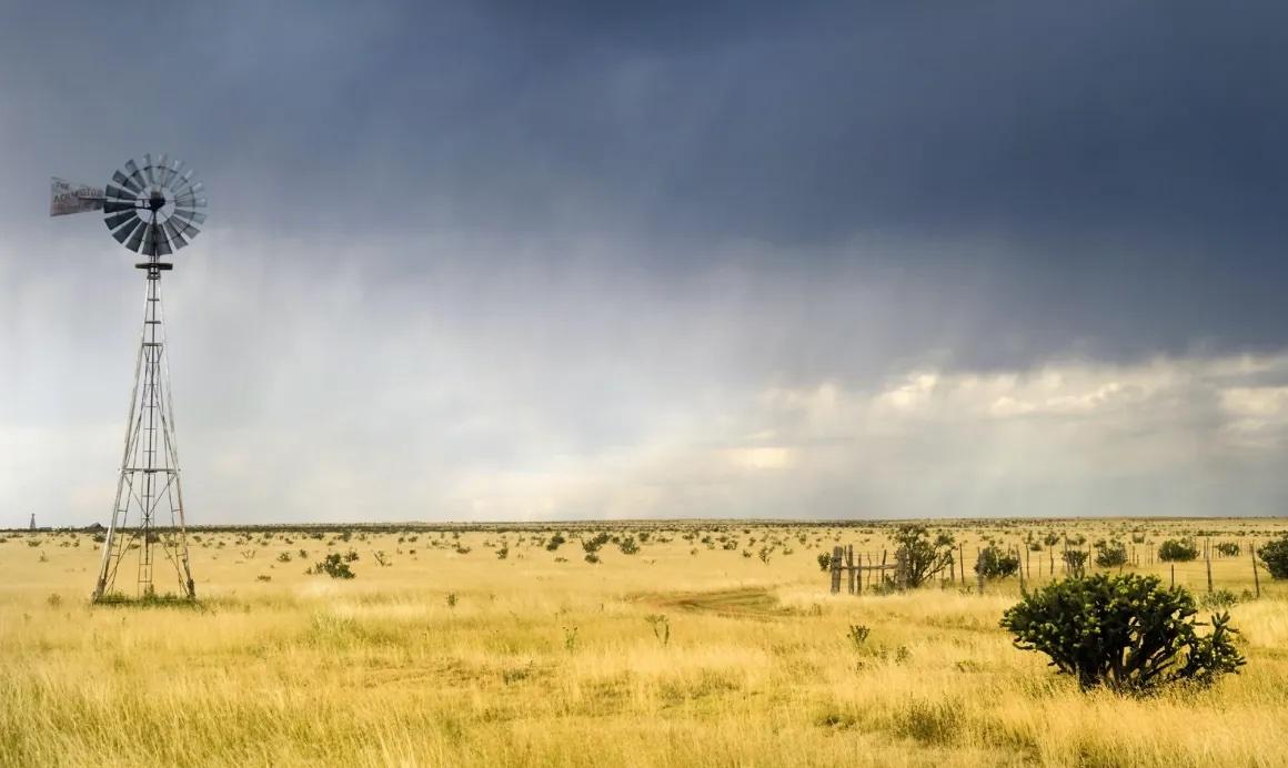 A windmill in a field before a storm in the Southern Plains.