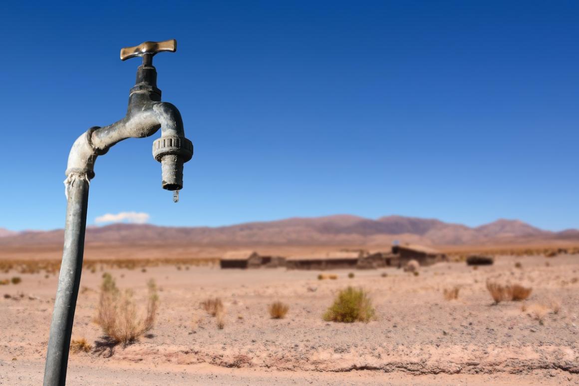 Water drips from a faucet in a dry landscape