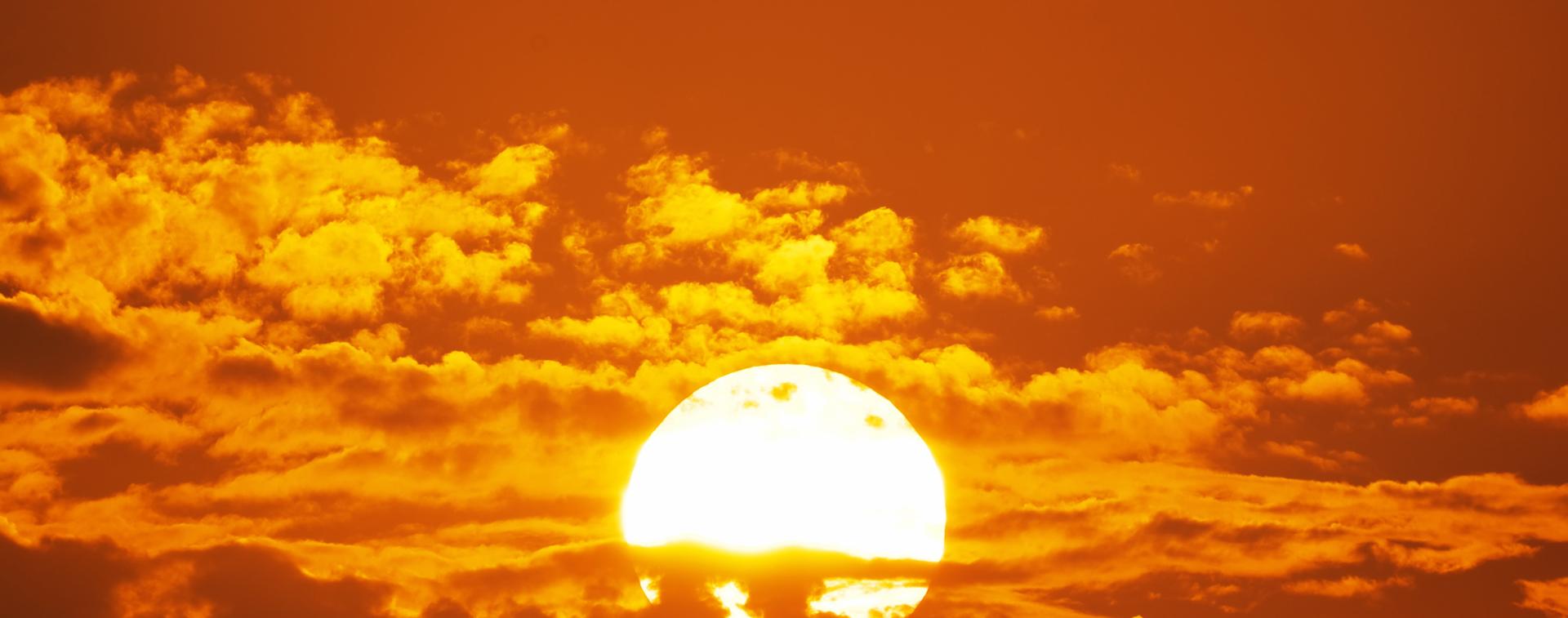 The sun shines red through the clouds, representing heat and drought.