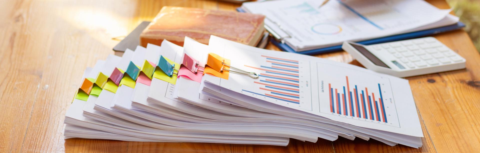 Stack of documents on a desk, representing research. Photo credit: thatinchan, Adobe Stock.