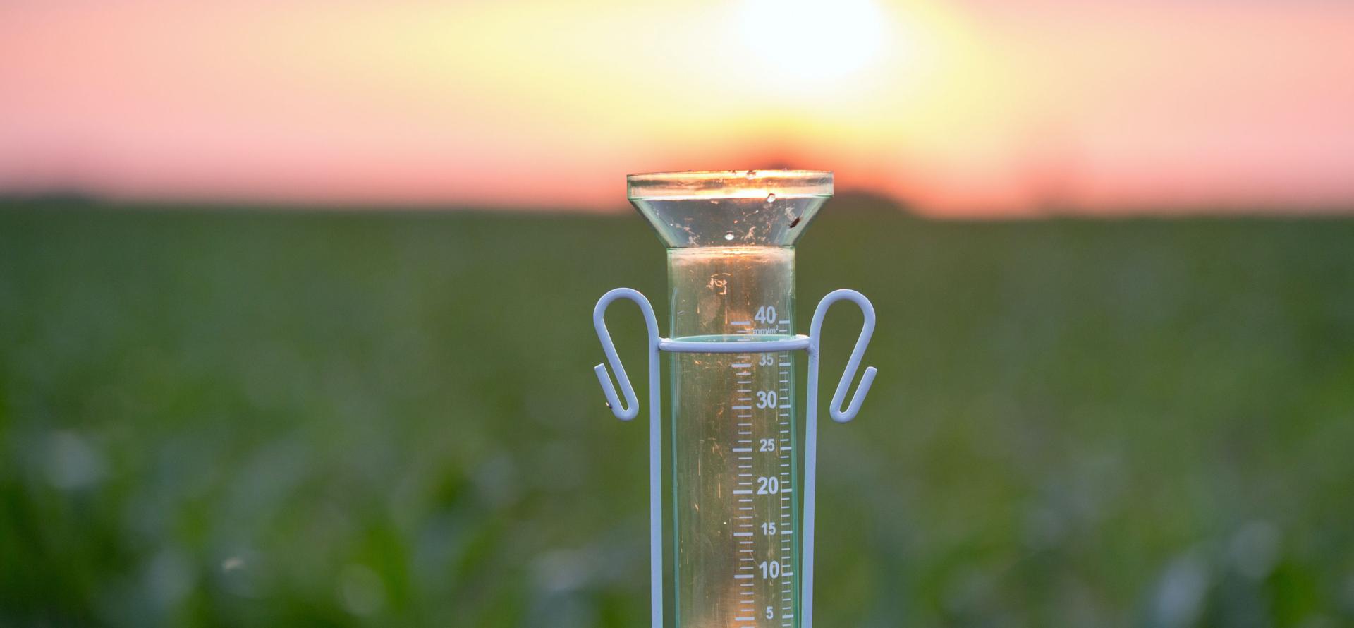 Rain gauge for water measurement in a field at sunset