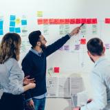 A group of people pointing to post-it notes on a white board, representing drought planning. Photo credit: Shutterstock, GaudiLab.