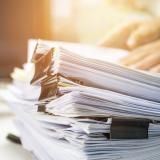 A stack of reports on a table. Photo credit: smolaw11, Adobe Stock.