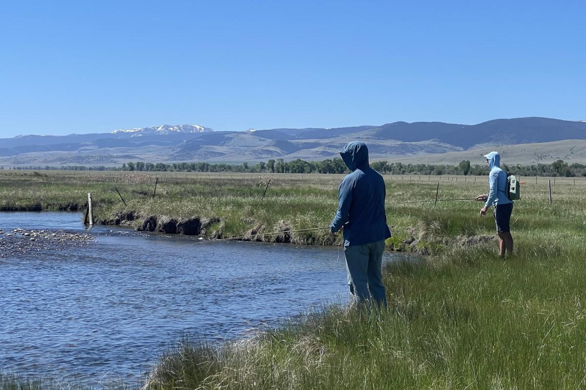 Two anglers on the banks on a Montana river with snow-capped mountains in the background. Photo by the U.S. Geological Survey.