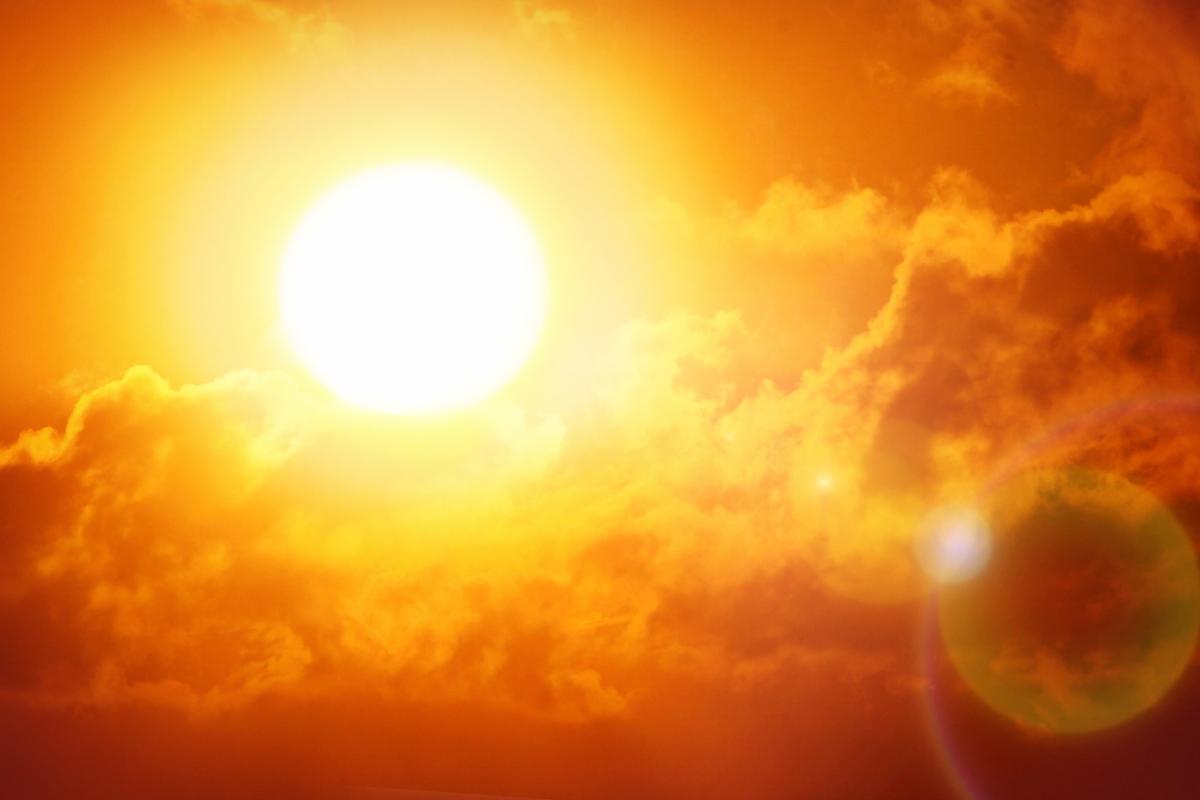 The sun shines brightly among clouds in a red sky, representing a heat wave. Photo credit: Shutterstock, Ed Connor.